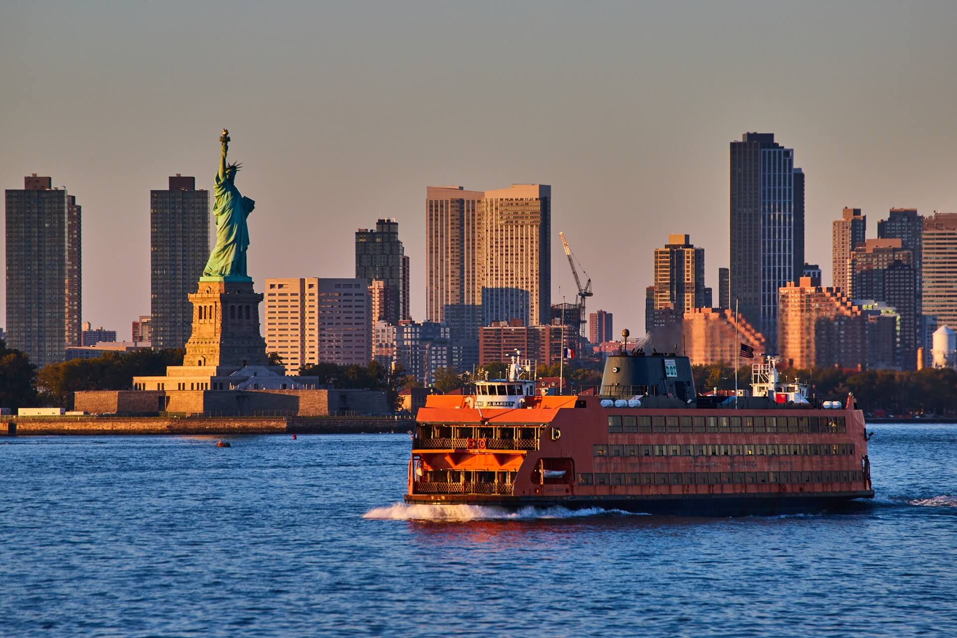 NYC ferry in the hudson with nyc skyline and statue of liberty