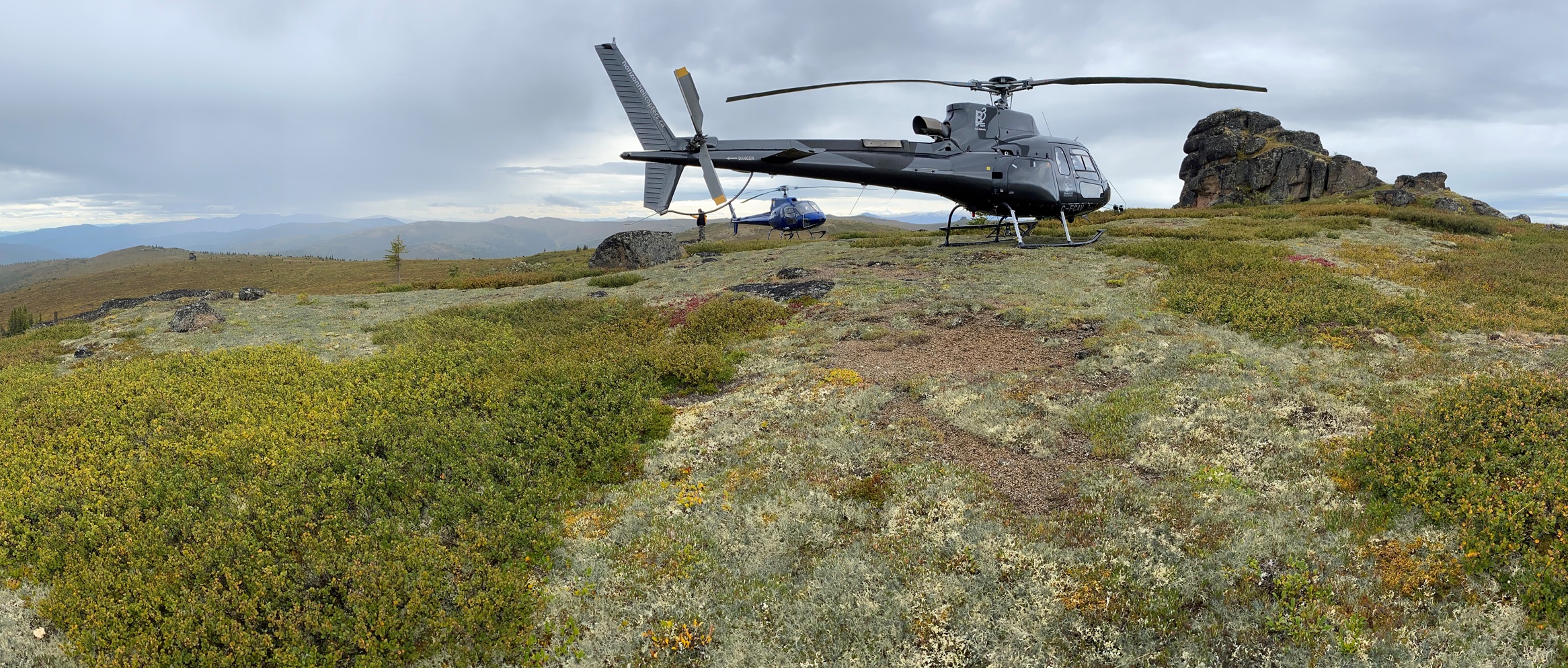 helicopter on grassy open field in the mountains
