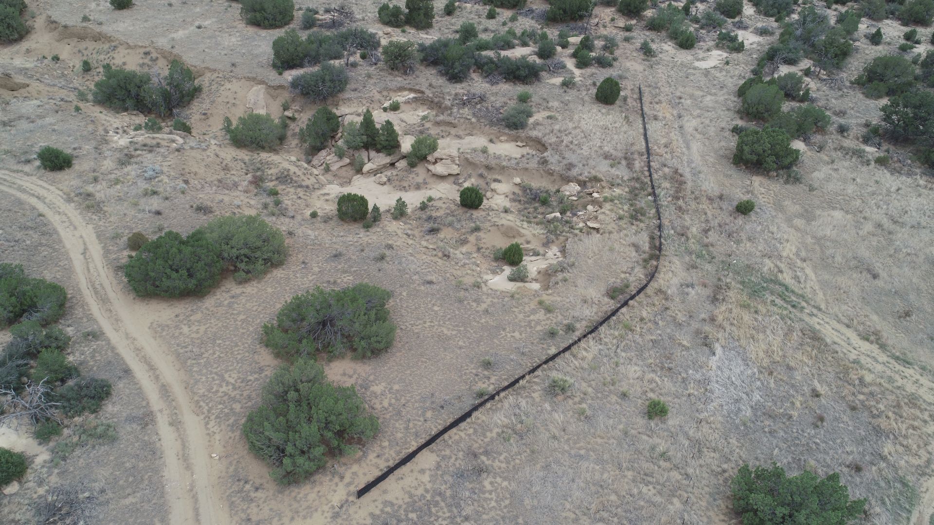 aerial view of dirt and dry mountain bushes with black fenced area