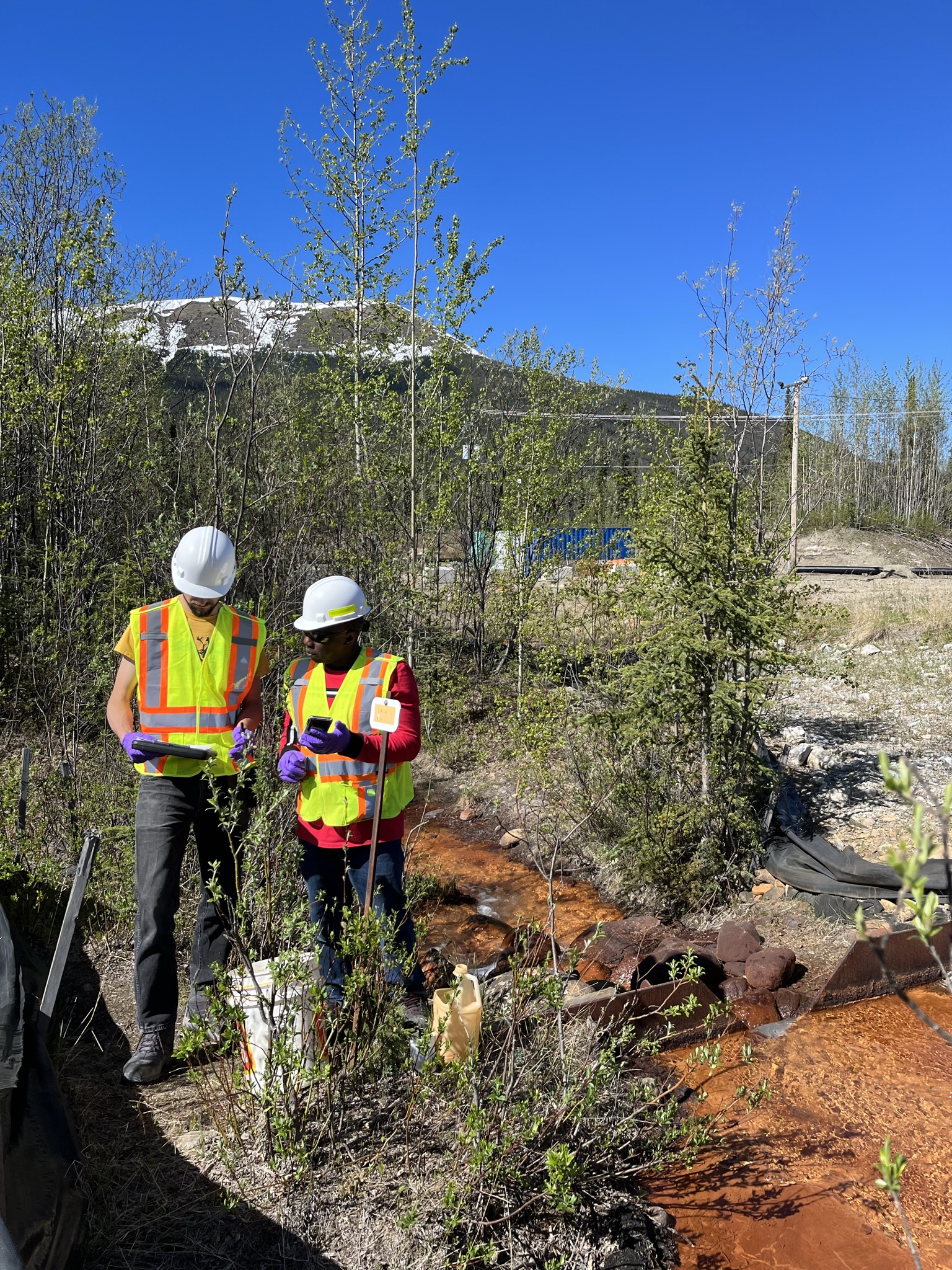 2 team members in high visibility vests in mountain area