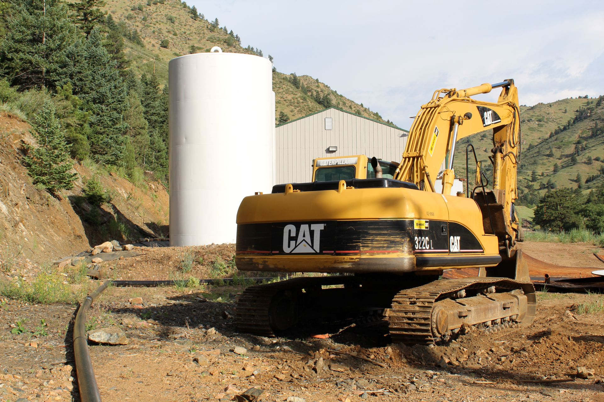 large excavator on site with silo and buildings in distance