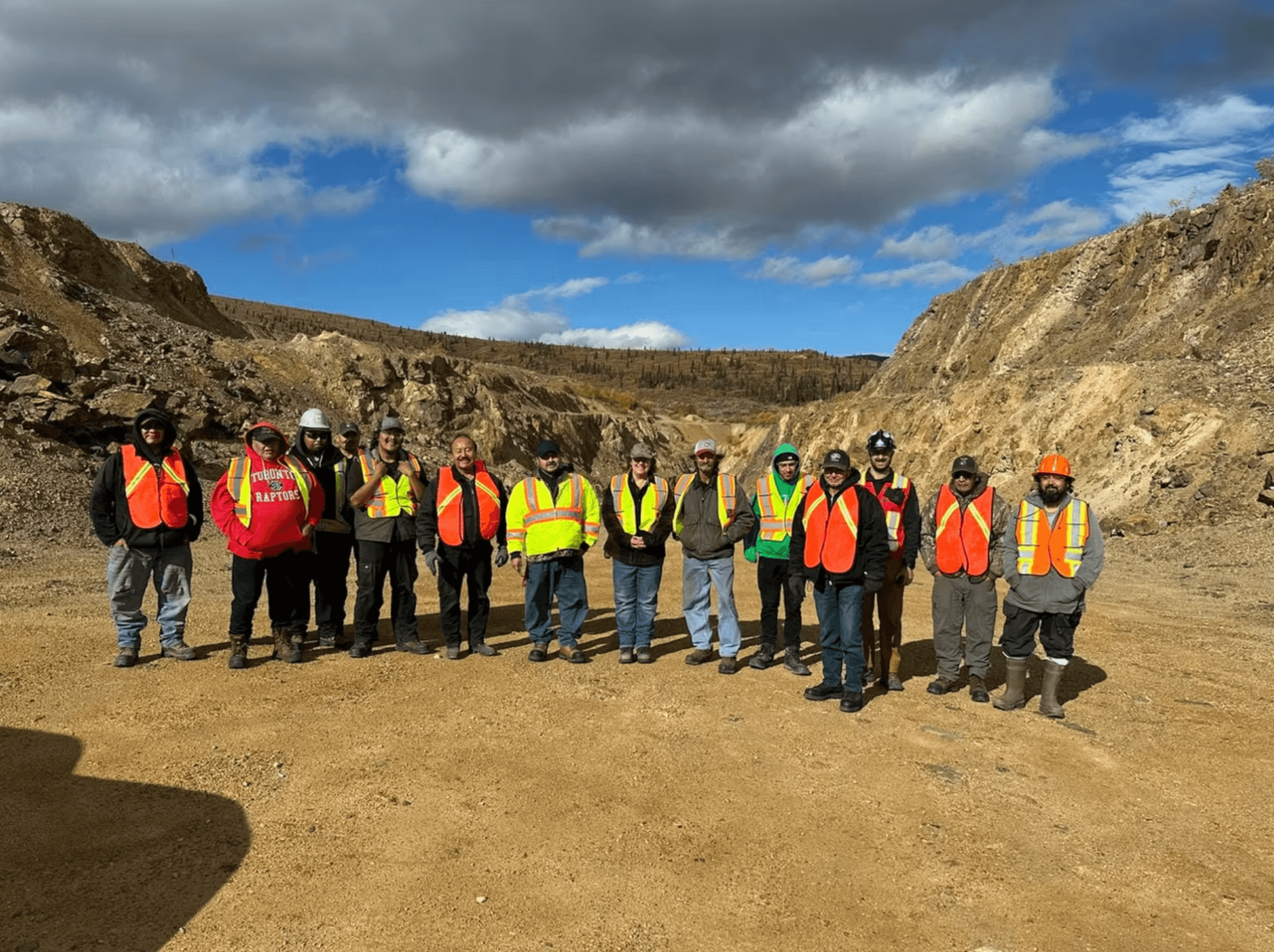 a dozen team members on the job site in the mountains in high visibility vests