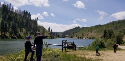 people at rivers edge with mountains in the distance