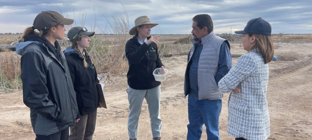 group of 5 people talking in desert area
