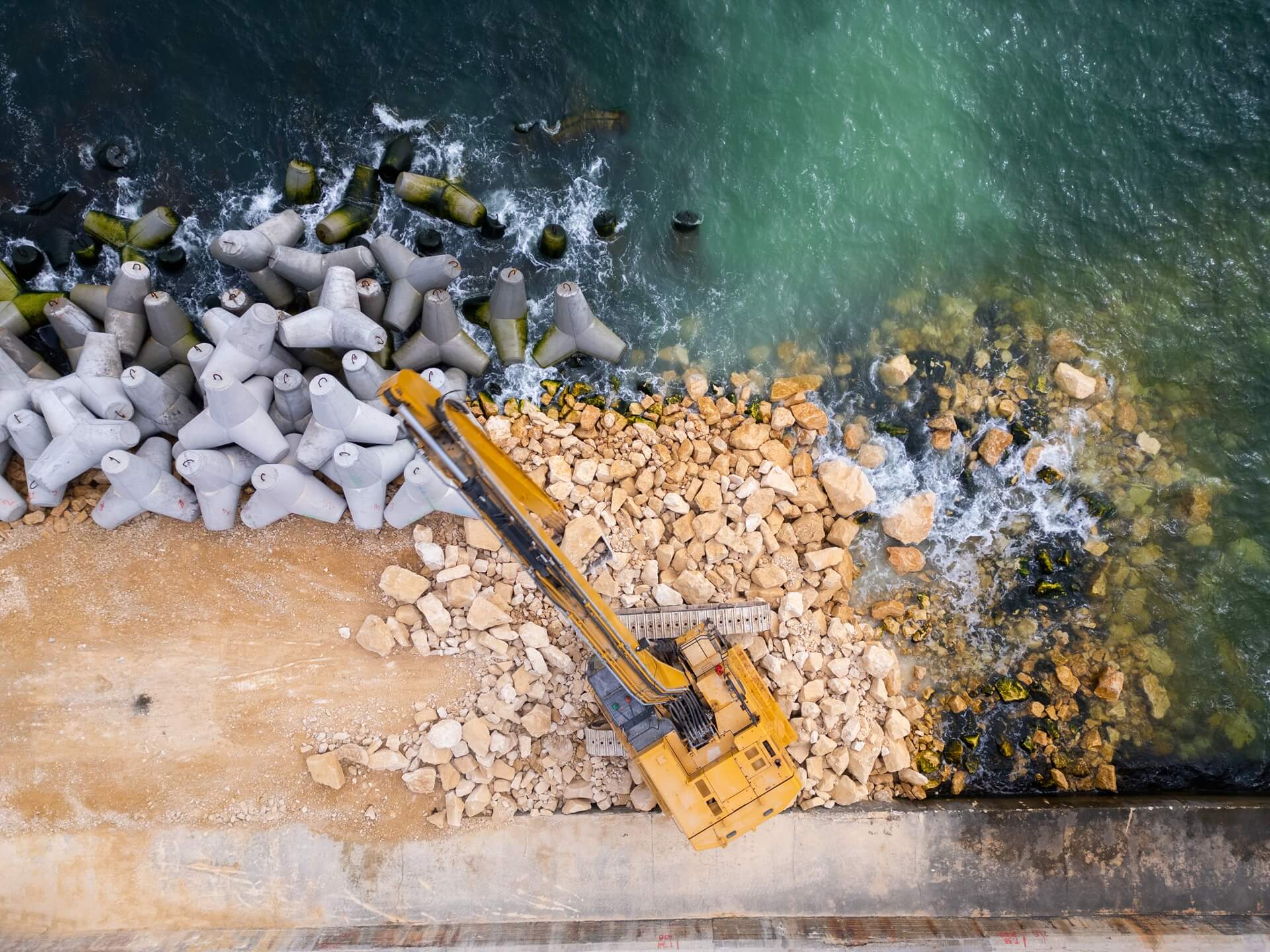 aerial view of construction vehicle on rocky coastline