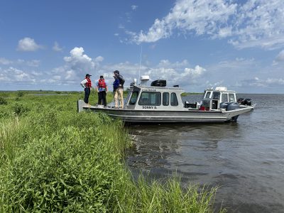 team members on river boat on coastal wetland