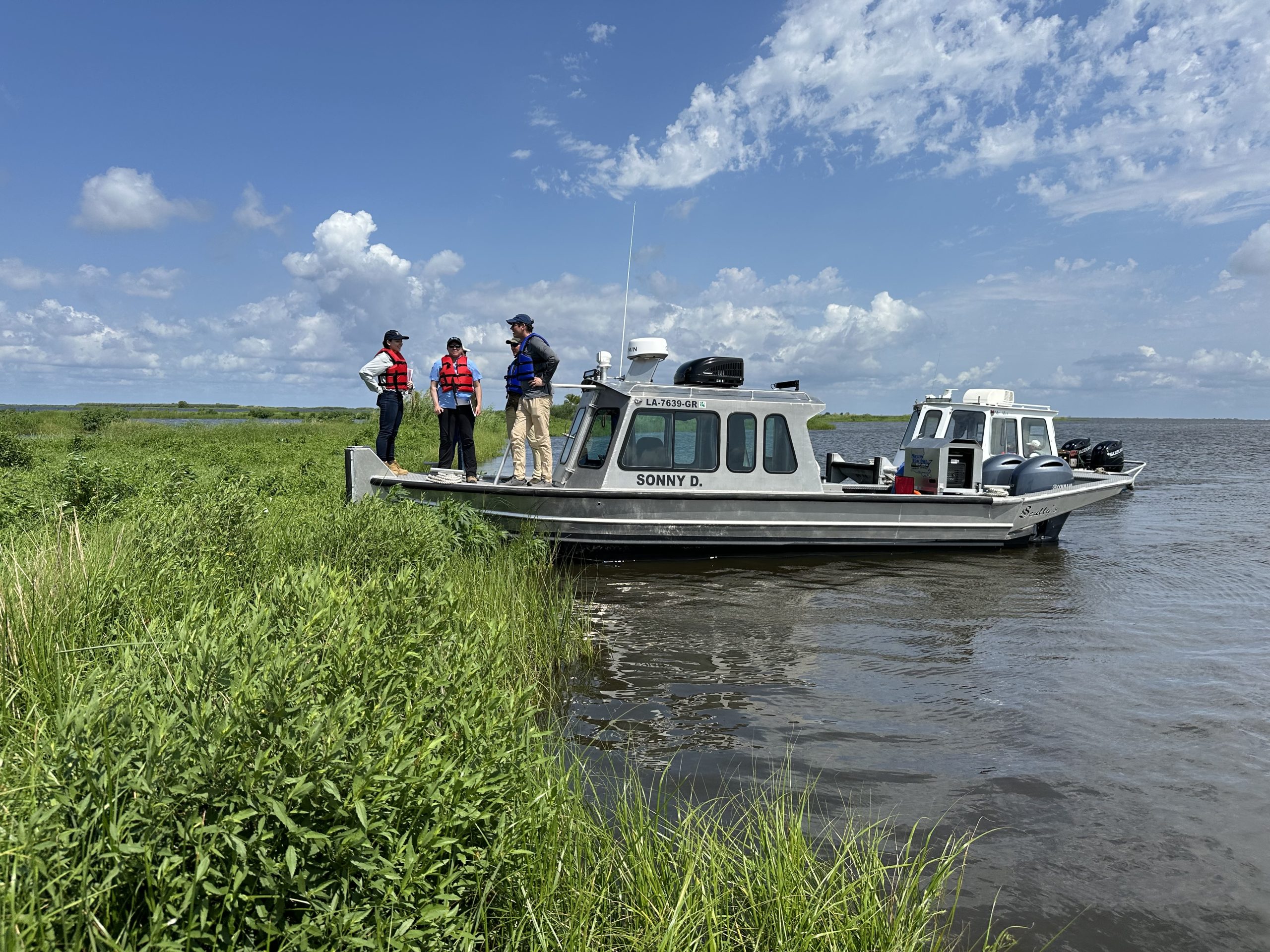 team members on river boat on coastal wetland