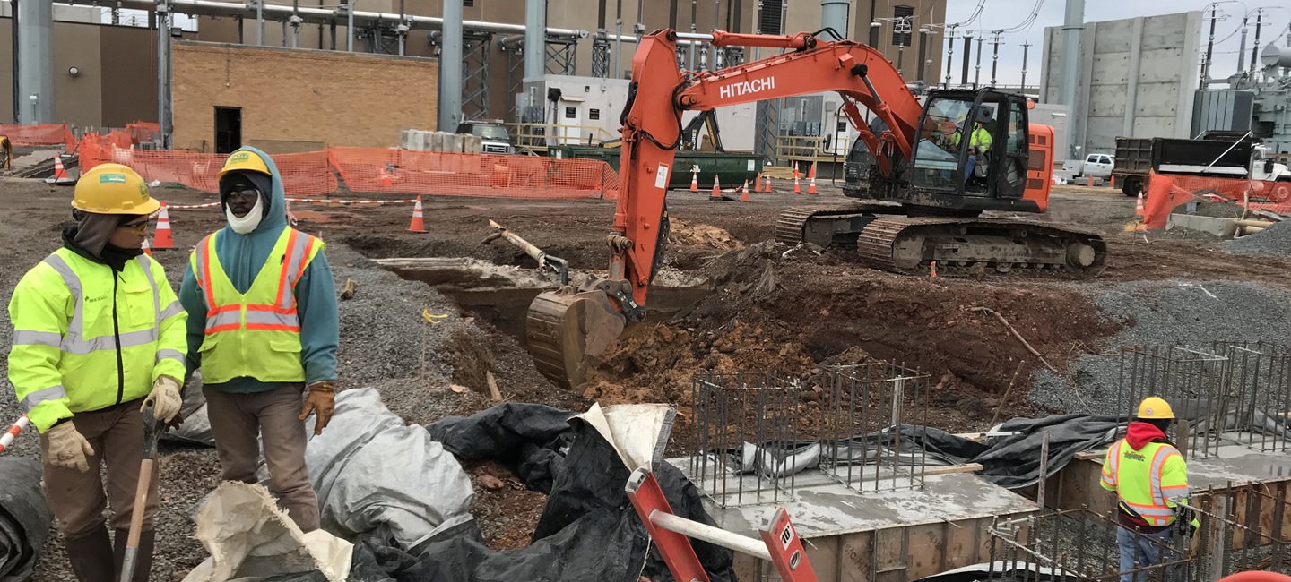 construction workers on site with equipment and a large hole