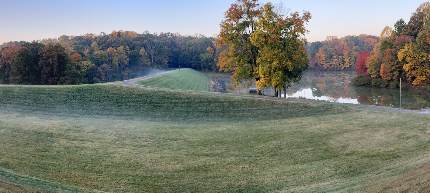 foggy hills by dam body of water and trees