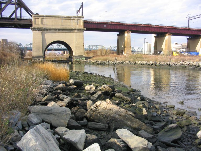 randalls island before, with rocky shoreline and no vegetation, with bridge in background
