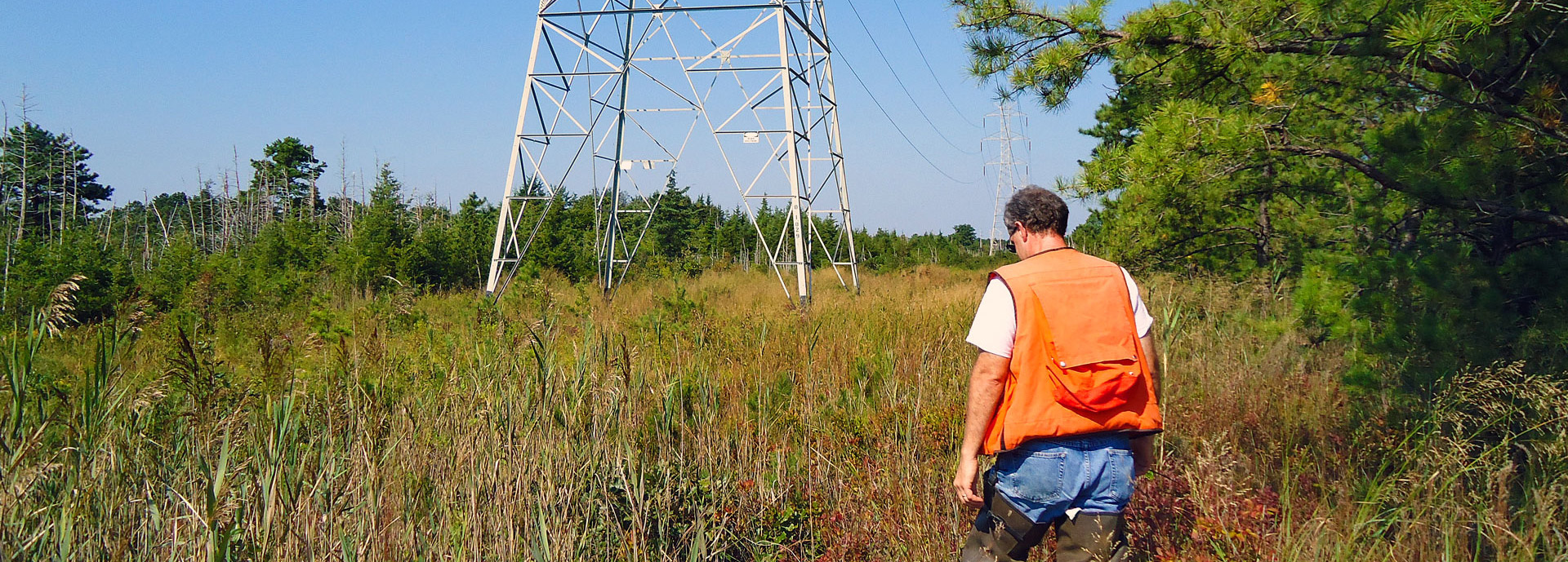 man in high vis vest walking in open field