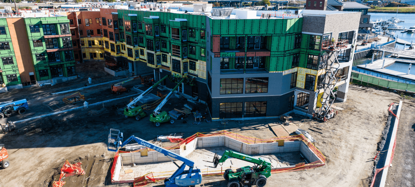 side view of building under construction with several large equipment on the ground