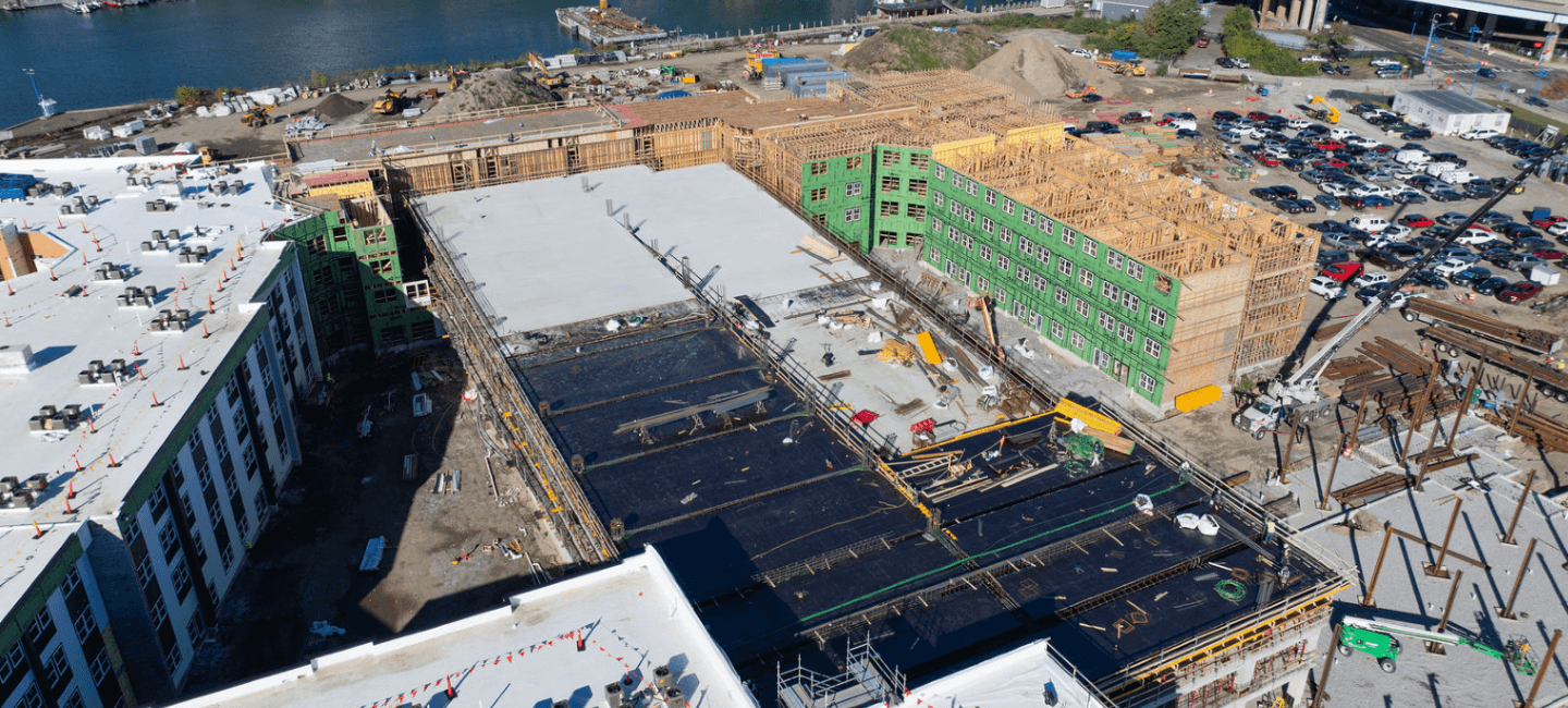 aerial view of building under constriction with river in distance and black tarps on roof