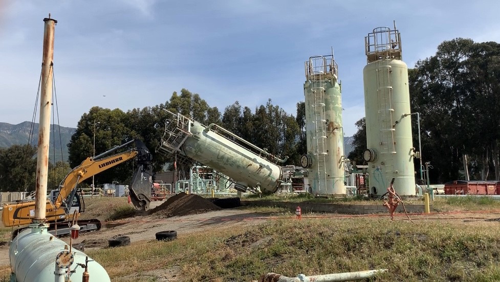 excavator working at site with tall silos