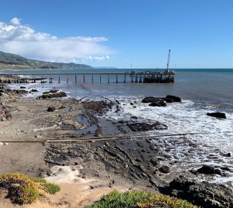 platform and pier off California coast with waves on rocky coast